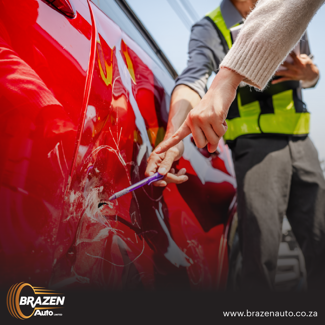 Person inspecting damage on a red accident-damaged car