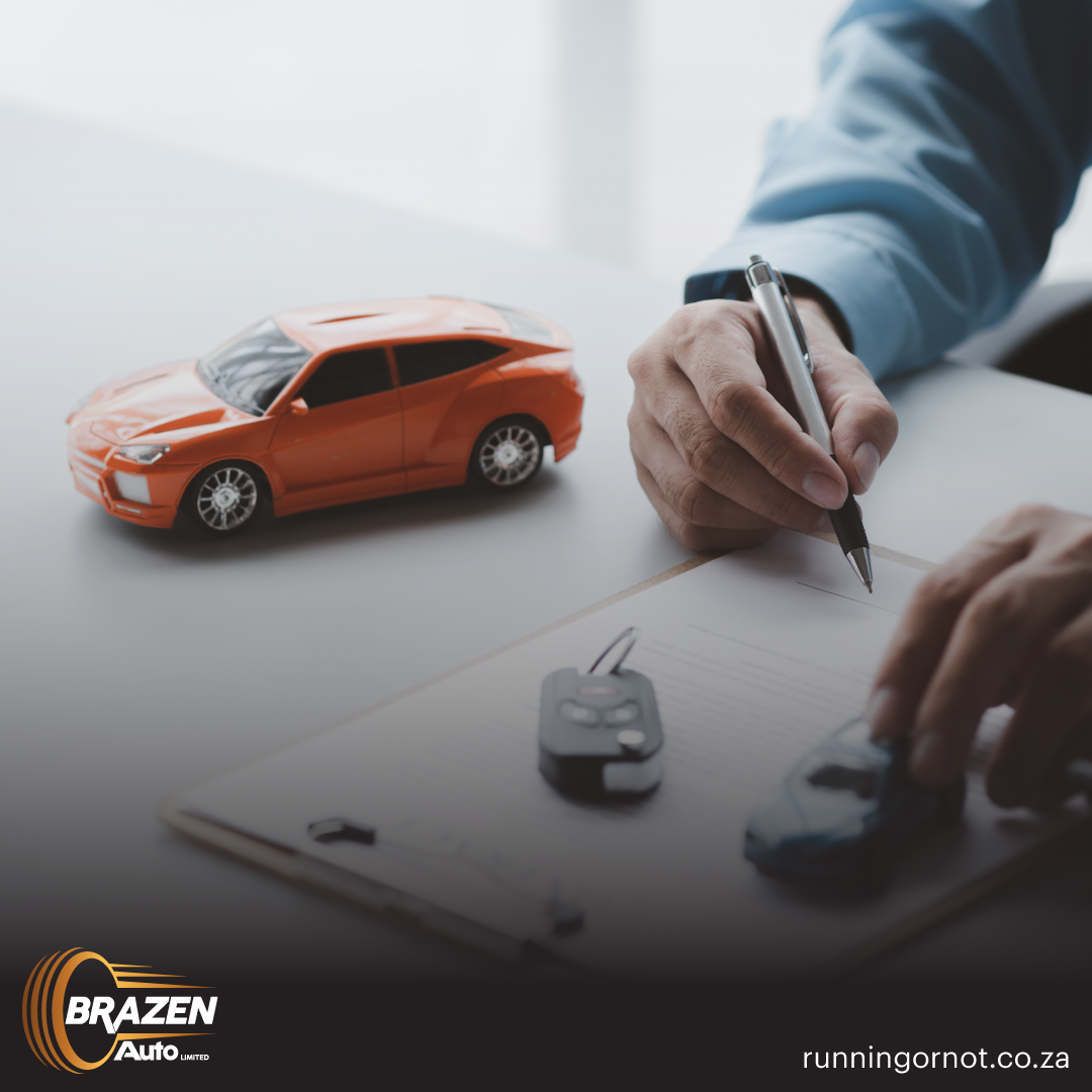 Person signing car sale paperwork with car key and model car on desk.